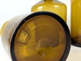 two yellow glass bottles sitting next to each other on a white surface