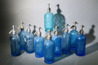 Plusieurs bouteilles en verre bleu équipées de distributeurs de savon sont alignées sur une table