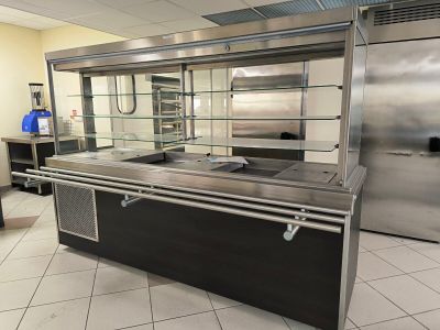 une cuisine équipée de plans de travail en inox et d'une vitrine en verre