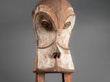 an old wooden sculpture of a face with two legs