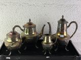 five silver teapots sitting on a tray on a table