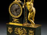 a gold and black clock with a statue on top of it