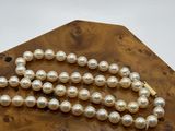 pearl necklace on a wooden stand with a white background