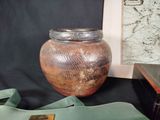 a brown vase sitting on a table next to a green bag