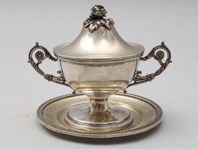 un service en argent ancien composé d'une assiette et d'une soucoupe posée dessus