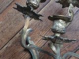 a metal candle holder on a wooden floor next to a clock