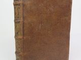 an old book sitting on top of a white table next to a white wall