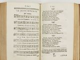 an open book with music notes on it sitting on a table