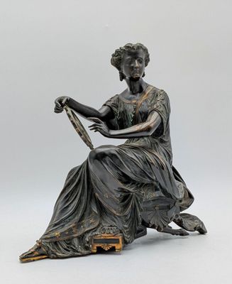 statue en bronze représentant une femme assise sur une chaise, un livre à la main