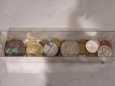 une boîte transparente remplie de différentes pièces de monnaie
