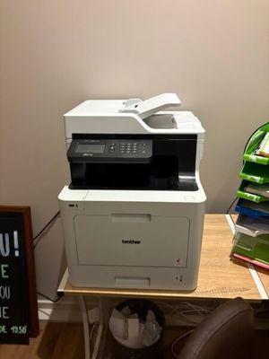 une imprimante posée sur un bureau, à côté d'un tableau noir