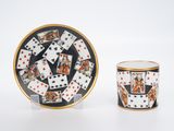 une image représentant une tasse et une soucoupe sur lesquelles sont posées des cartes à jouer