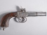un pistolet ancien plaqué argent, avec une crosse en bois, posé sur une surface blanche
