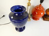a blue vase sitting on a table next to a lamp