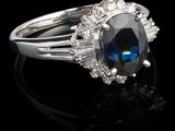une bague ovale sertie d'un saphir bleu et de diamants, posée sur un fond noir