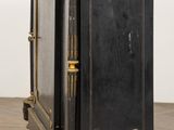 an antique black and gold painted cabinet on wheels on a wooden floor