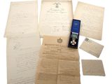 Plusieurs vieux documents et une médaille sont exposés sur une table