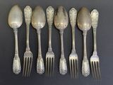 six cuillères en argent et une fourchette sont alignées sur une table