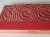un vieux livre à la couverture rouge posé sur une surface blanche