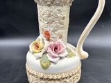 a white vase with a pink rose on it on a table