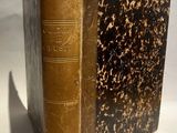 un vieux livre posé sur une table à côté d'un mur blanc
