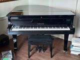 a black piano sitting in a living room next to a chair