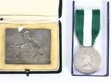 an old silver medal with a green ribbon in a box