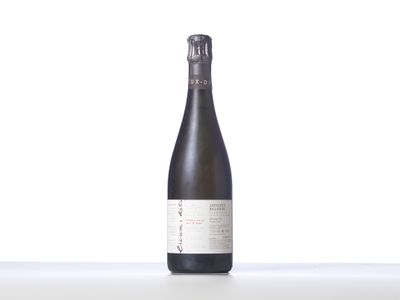 une bouteille de vin posée sur une table à côté d'un mur blanc