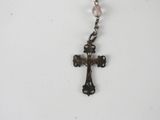 a silver cross with a pink bead hanging from it