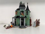 une maison verte avec un toit noir et une porte noire