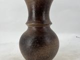 a brown vase that is sitting on a white surface