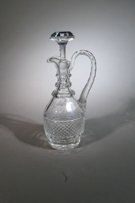a clear glass vase with a handle on a table