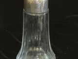 une cloche en verre transparent avec un couvercle argenté sur fond noir