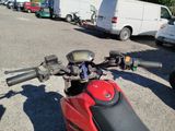 a red motorcycle parked in a parking lot next to a white van