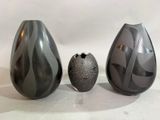 trois vases posés l'un à côté de l'autre sur une table