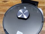 un gros plan d'un robot aspirateur posé sur une table en bois