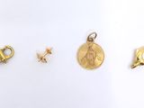 three gold charms and a gold coin on a white surface