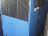 un climatiseur bleu posé dans une pièce, à côté d'une chaise