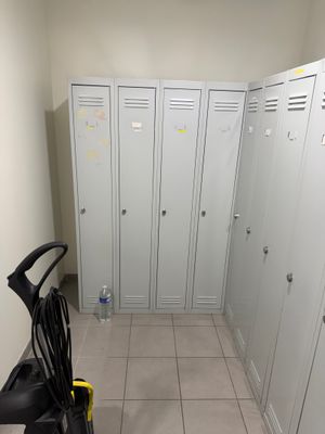 plusieurs casiers dans le couloir d'un immeuble, avec un balai et une serpillière