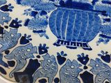 a blue and white plate with a vase of flowers on it