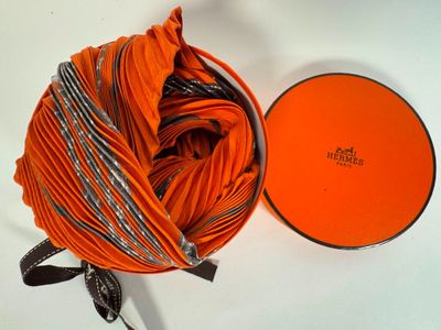 une boîte orange posée sur une surface blanche, avec une pelote de laine à côté