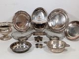 a lot of silver dishes and bowls sitting on a table