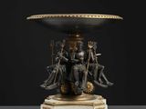 un vase noir et doré sur lequel sont assises quatre personnes
