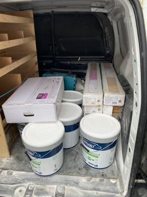 boxes and buckets of paint sit in the back of a van