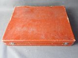 an old orange suitcase sitting on top of a gray surface
