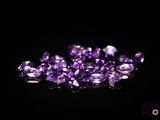 un gros plan sur un tas de pierres précieuses violettes posées sur une surface noire