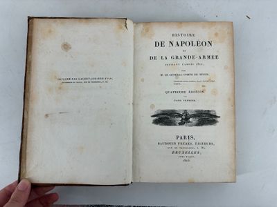 someone is holding a book open on a white surface