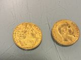 two gold coins that are sitting on a table