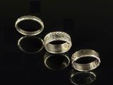 three silver rings sitting on top of a table next to each other