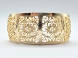a close up of a gold bracelet on a white surface